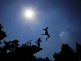 Dos jóvenes saltan desde un trampolín de 5 metros en una piscina en Grossröehrsdorf, Alemania. Meteorólogos señalaron que los termómetros alcanzarán los 40 grados centígrados debido a la ola de calor que sufre Europa.