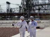 Dos trabajadores caminan frente a una planta nuclear ucraniana en funcionamiento.