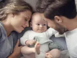 Imagen de una pareja de padres con el bebé en la cama