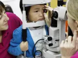 Una oculista realiza una revisión ocular a un niño.