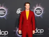 El actor Patrick Schwarzenegger, en rojo y amarillo, posa para los fotógrafos en la alfombra roja de los American Music Awards 2019.