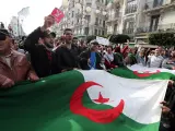 Varias personas sostienen la bandera argelina durante una protesta en la v&iacute;spera de las elecciones generales.