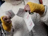 Una lotera entrega una tira de boletos de la Lotería del Niño.