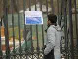 Un hombre lee el cartel que anuncia que El Retiro está cerrado por la borrasca.