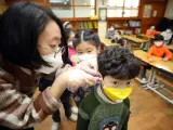 Una profesora toma la temperatura a un ni&ntilde;o en una escuela de Se&uacute;l, Corea del Sur, como medida preventina ante posibles contagios del coronavirus de Wuhan.