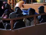 Algunos de los 33 inmigrantes subsaharianos rescatados cuando viajaban en una patera rumbo a Canarias, entre ellos 19 mujeres (dos de ellas embarazadas) y cinco menores de edad, a su llegada al puerto de Arguinegu&iacute;n, en Gran Canaria.