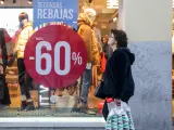 Una mujer pasea junto a una tienda de moda , en la que se ofertan las segundas rebajas con ofertas de hasta el 60%.