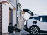 Mujer cargando su coche eléctrico en su casa.