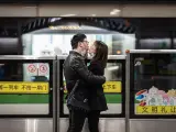 Una pareja se besa con sus mascarillas bajadas, mientras espera un tren en la estaci&oacute;n de la Plaza del Pueblo en Shanghai, China.