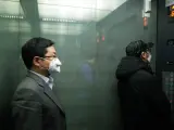 Dos personas con mascarillas por el coronavirus COVID-19, en un ascensor de Pek&iacute;n, China.
