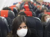 Una pasajera viaja con mascarilla en un avión