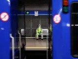 Un viajero del Metro de Madrid espera ataviado con un traje de pl&aacute;stico, guantes y mascarilla para evitar el contagio de coronavirus.