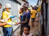 Un voluntario de una campa&ntilde;a contra el coronavirus reparte jab&oacute;n en una barriada de Johanesburgo.