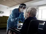 Una cuidadora ayuda a comer a una anciana en una residencia.