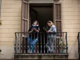 Dos jóvenes leen en el balcón de su casa con ocasión de la Diada de Sant Jordi, en la que es costumbre regalar libros y rosas, en Barcelona / Catalunya (España), a 23 de abril de 2020.