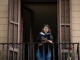 Una joven lee un libro en el balc&oacute;n de su casa con ocasi&oacute;n de la Diada de Sant Jordi, en la que es costumbre regalar libros y rosas, en Barcelona / Catalunya (Espa&ntilde;a), a 23 de abril de 2020.