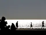 Varias personas disfrutan de un paseo, a primera hora, en la playa de la Malvarrosa en el horario establecido, tras no haber pasado a la fase 1.