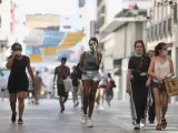 Varias personas caminan por la calle Preciados de Madrid en plena ola de calor.