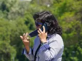 Una mujer se quita la mascarilla para hablar por tel&eacute;fono mientras pasea por el puente de triana en el primer d&iacute;a del uso obligatorio de mascarillas por el Covid-19. Sevilla a 21 de mayo del 2020