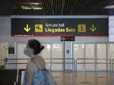 Una persona con mascarilla pasa junto a la entrada de la sala de llegadas 1 de la Terminal 1 del Aeropuerto de Barajas, en Madrid (España) a 4 de julio de 2020.
