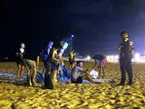 Un grupo de personas que hacía botellón en la playa de la Barceloneta se levantan ante la presencia de agentes de la Guardia Urbana.