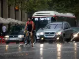 Un ciclista y varios turismos bajo la lluvia en la Avenidad del Paral·lel de Barcelona, en una imagen de archivo.
