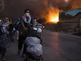 Varias familias de migrantes huyen con lo poco que han podido salvar de las llamas, del campo de Moira, en Lesbos (Grecia), que ha sido casi totalmente destruido por varios incendios simult&aacute;neos.