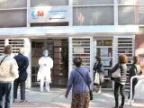 Una sanitaria sale a atender a las numerosas personas que hacen cola en el Centro de Salud Vicálvaro-Artilleros en el distrito de Vicálvaro, en Madrid.