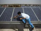 Un trabajador limpia una placa solar en la azotea de un edificio.