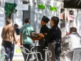 Dos camareros trabajan en una de las terrazas ubicadas en el Paseo del Prado, v&iacute;a peatonalizada durante este fin de semana, en Madrid