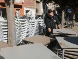 El propietario de un bar recoge las sillas y mesas de la terraza tras el cierre decretado por la Generalitat, el pasado 16 de octubre.