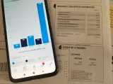 Una factura junto a un móvil con gráficos