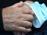 Una persona mayor toma una mascarilla entre sus manos