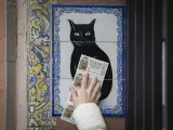 Una persona pasa varios décimos de la lotería de Navidad por el azulejo de la administración 'El gato negro', en Sevilla.