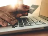 Persona usando un ordenador con tarjeta de crédito y haciendo compras online.
