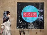 Una mujer ante un graffiti en la capital de Irán, Teherán, durante la pandemia de coronavirus.