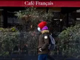 Una persona con mascarilla por el coronavirus pasa junto a un café cerrado por la pandemia, en París, Francia.