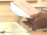 Un elector con las papeletas junto a la urna (Archivo)