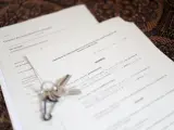 Unas llaves sobre un contrato de compraventa de vivienda y un contrato de arrendamiento (alquiler) de una habitación en una vivienda compartida.