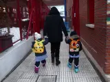 Un familiar lleva de la mano a dos alumnos del colegio Arcangel Rafael el día de la reapertura de los centros educativos tras la gran nevada registrada por el paso de ‘Filomena’, en Aluche, Madrid, (España), a 20 de enero de 2021. El