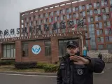 Un miembro del equipo de seguridad intenta evitar que se tomen fotografás del Instituto de Virología de Wuhan, en China.