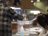 Una mujer deposita su voto en una urna en en un colegio electoral de Barcelona.