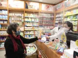 Una anciana recoge una mascarilla FFP2 en la farmacia situada en Carabanchel