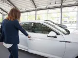 Archivo - Una mujer abre un coche en un concesionario