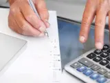 Archivo - Una persona haciendo cálculos con una hoja y una calculadora