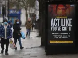 Un cartel del sistema público de salud británico sobre el coronavirus, con el mensaje "Actúa como si lo tuvieses, cualquiera puede transmitirlo", en Londres.