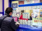 Archivo - Una persona compra un décimo para el Sorteo Extraordinario de la Lotería de Navidad en una administración de Madrid