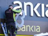Un operario retira el rótulo de Bankia de la sede principal del banco en Logroño este sábado.