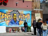Un grafiti con la imagen de George Floyd y flores en su memoria, en el lugar donde el afroamericano murió a manos de un policía mientras era arrestado, en Mineápolis (Minnesota, EE UU).