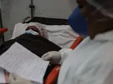 Una trabajadora sanitaria lee a un paciente de covid-19 una carta escrita por los familiares del enfermo, en un hospital de R&iacute;o de Janeiro (Brasil).